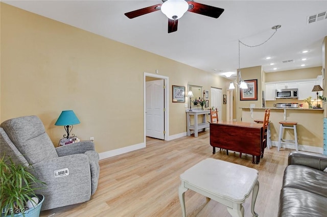 living area with visible vents, baseboards, ceiling fan, light wood-style floors, and recessed lighting