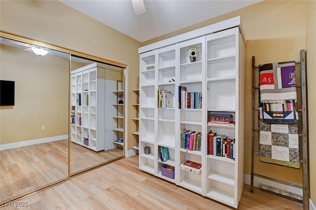 interior space with a closet, wood finished floors, a ceiling fan, and baseboards