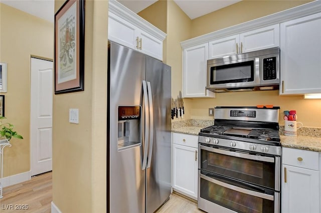 kitchen with white cabinets, light wood finished floors, stainless steel appliances, and light stone countertops