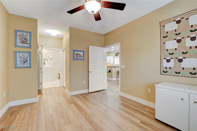 interior space featuring ceiling fan, light wood-style flooring, and baseboards