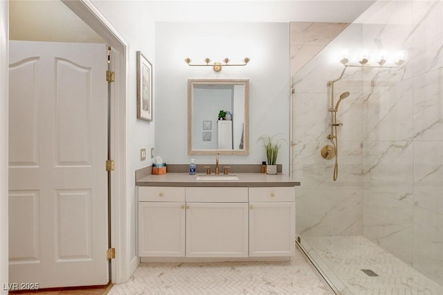 full bath featuring a marble finish shower and vanity