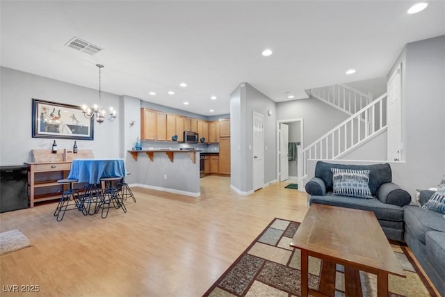 living room with a notable chandelier, recessed lighting, visible vents, light wood-style floors, and stairs