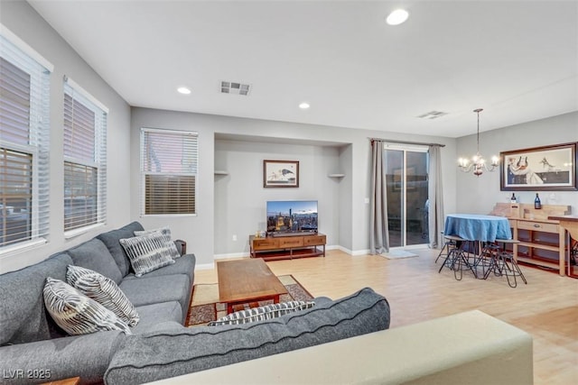 living area with recessed lighting, visible vents, light wood-style flooring, and an inviting chandelier