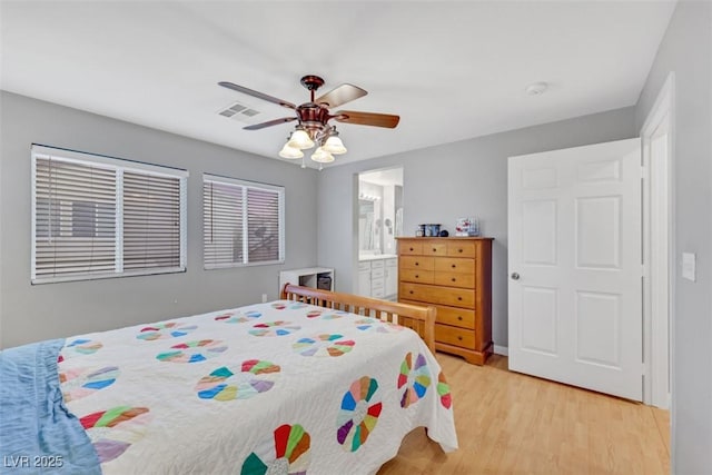 bedroom with a ceiling fan, light wood-type flooring, visible vents, and connected bathroom