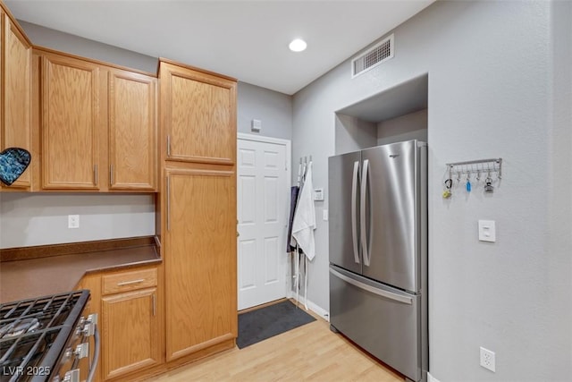 kitchen with light wood-style flooring, recessed lighting, stainless steel appliances, visible vents, and dark countertops