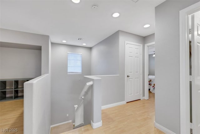 corridor with light wood finished floors, recessed lighting, visible vents, an upstairs landing, and baseboards