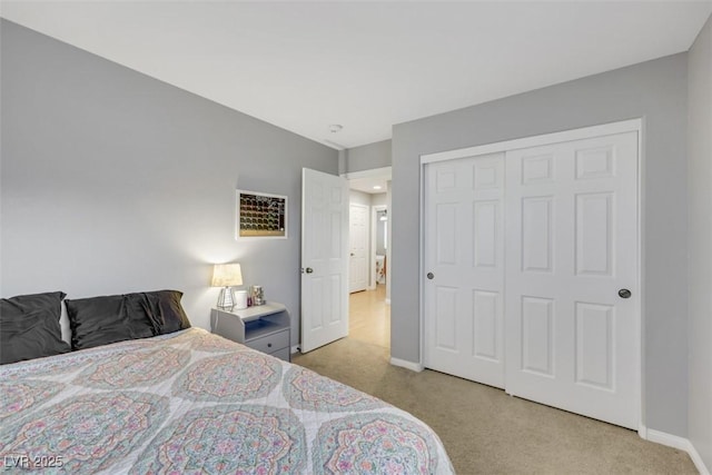 bedroom featuring baseboards, a closet, and light colored carpet