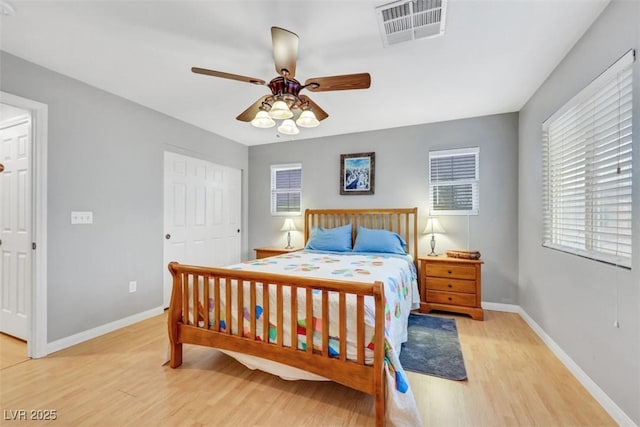 bedroom with light wood-type flooring, visible vents, ceiling fan, and baseboards