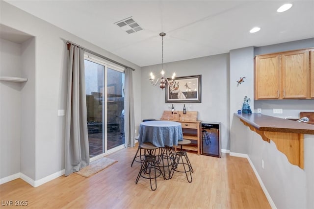 dining room with visible vents, a notable chandelier, light wood-style flooring, and baseboards