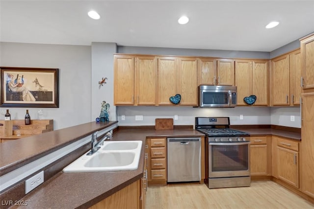 kitchen featuring stainless steel appliances, light wood-style floors, a sink, and recessed lighting