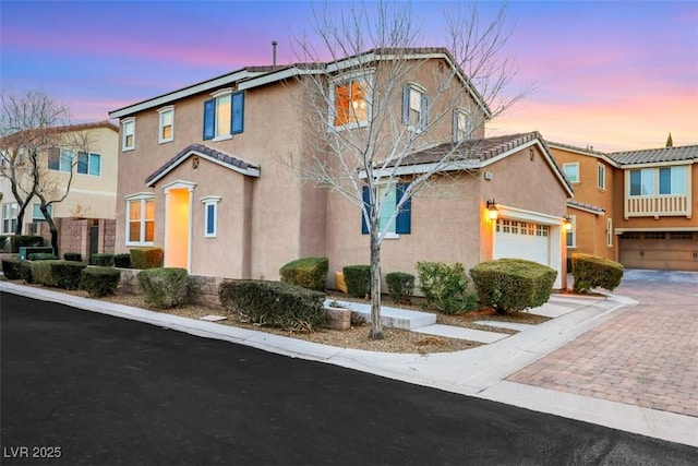 view of front of home featuring decorative driveway, an attached garage, and stucco siding