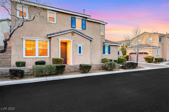 view of front of home featuring driveway, an attached garage, and stucco siding