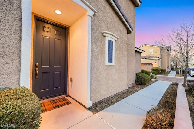 exterior entry at dusk with stucco siding