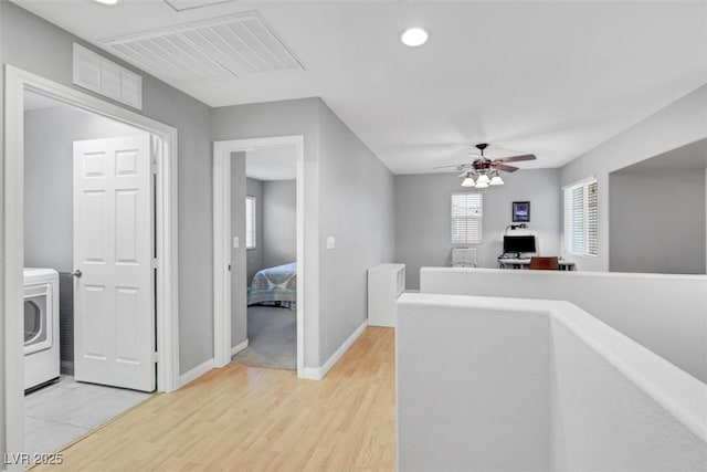 corridor with light wood finished floors, washer / clothes dryer, an upstairs landing, and visible vents