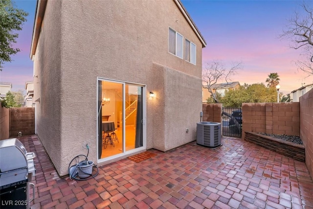 back of property at dusk with a patio area, fence, and stucco siding