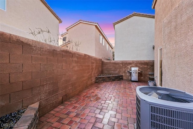 patio terrace at dusk featuring a fenced backyard and central AC