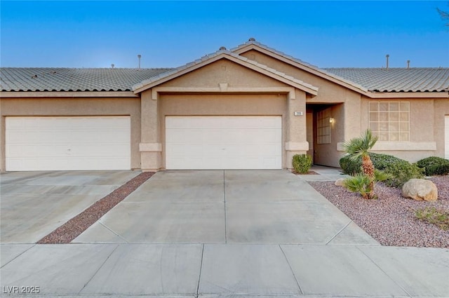 ranch-style house with a garage, a tiled roof, concrete driveway, and stucco siding