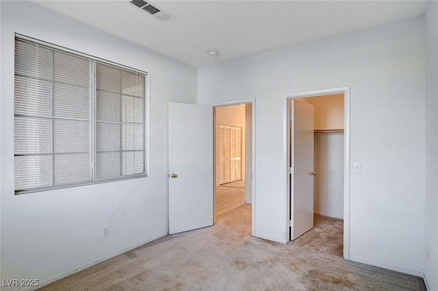 unfurnished bedroom featuring carpet floors, a spacious closet, and visible vents