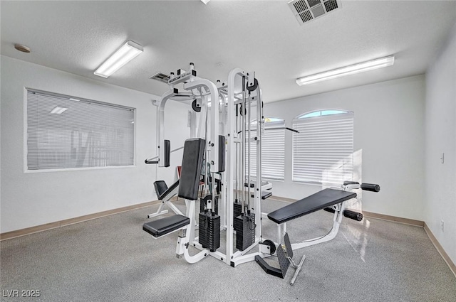 exercise area with a textured ceiling, visible vents, and baseboards