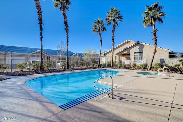 community pool with fence and a hot tub