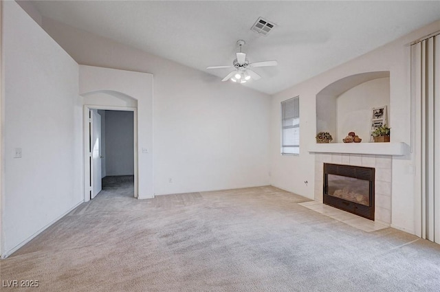 unfurnished living room with ceiling fan, visible vents, a tiled fireplace, and carpet flooring