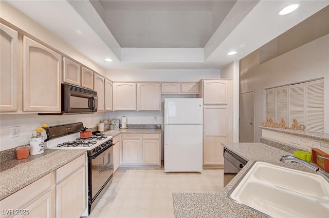 kitchen with light floors, recessed lighting, a sink, black appliances, and a tray ceiling