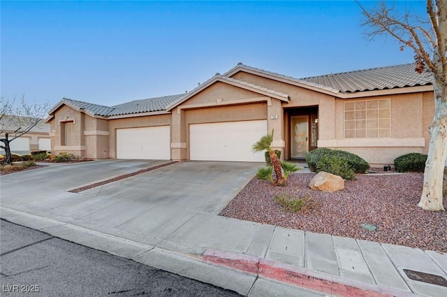 ranch-style home featuring concrete driveway, an attached garage, a tile roof, and stucco siding