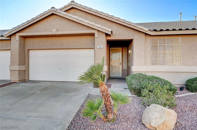 view of property featuring a garage, driveway, a tile roof, and stucco siding