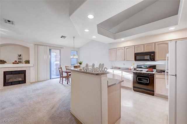 kitchen featuring black microwave, visible vents, gas stove, freestanding refrigerator, and a tiled fireplace