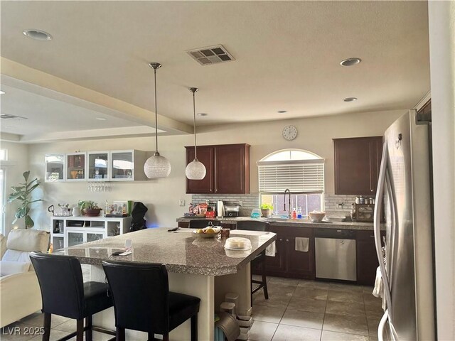5320 Tartan Hill Ave, Las Vegas, NV 89141 - kitchen with tasteful backsplash, visible vents, appliances with stainless steel finishes, decorative light fixtures, and a kitchen bar