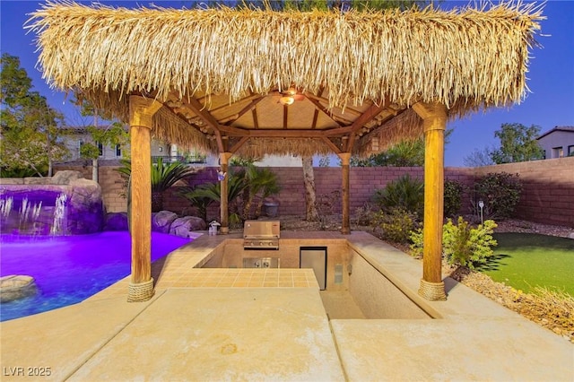 view of patio featuring a gazebo, a fenced backyard, grilling area, and an outdoor kitchen