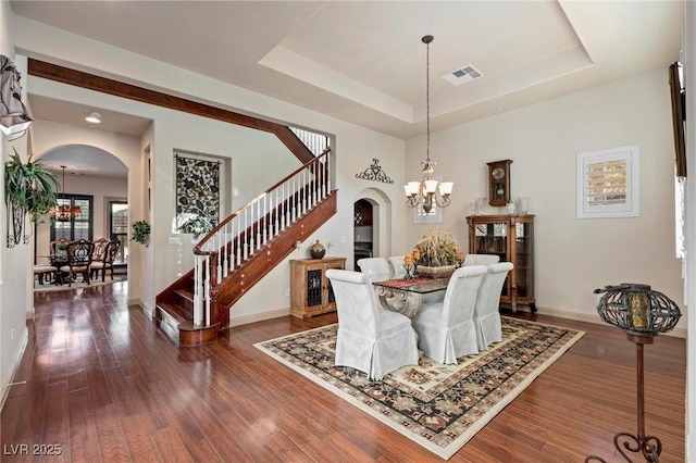 dining area featuring a chandelier, a tray ceiling, arched walkways, and visible vents