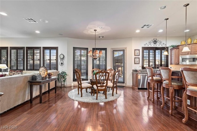 dining space featuring dark wood-style floors, visible vents, and a chandelier