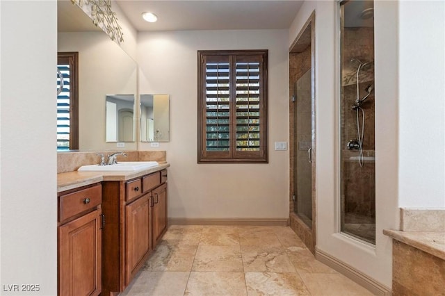 full bathroom featuring plenty of natural light, a shower stall, baseboards, and vanity