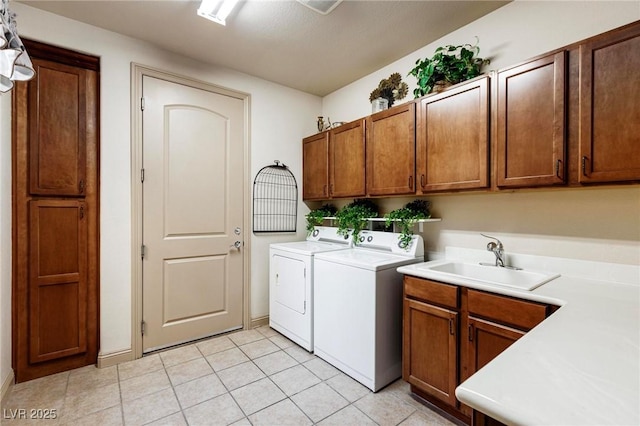 clothes washing area with washing machine and dryer, cabinet space, a sink, and light tile patterned flooring