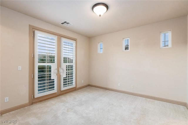 empty room featuring plenty of natural light, carpet, visible vents, and baseboards