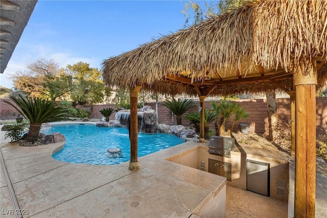 view of pool featuring an outdoor kitchen, a fenced in pool, a fenced backyard, a grill, and a patio area