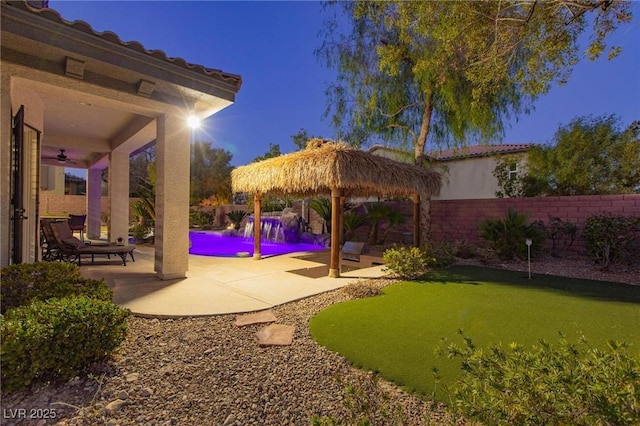 view of yard featuring a patio, a fenced backyard, a fenced in pool, and a ceiling fan