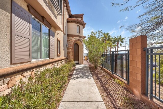 view of exterior entry with a gate, stone siding, and fence