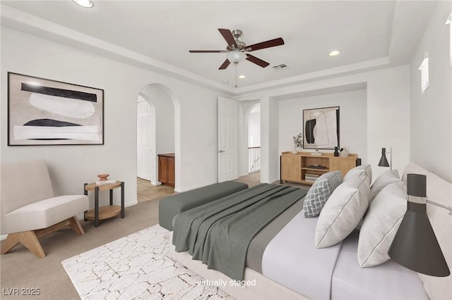 bedroom featuring visible vents, recessed lighting, arched walkways, light carpet, and a raised ceiling