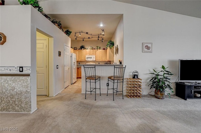 kitchen featuring light colored carpet, light brown cabinets, white appliances, a peninsula, and a kitchen breakfast bar