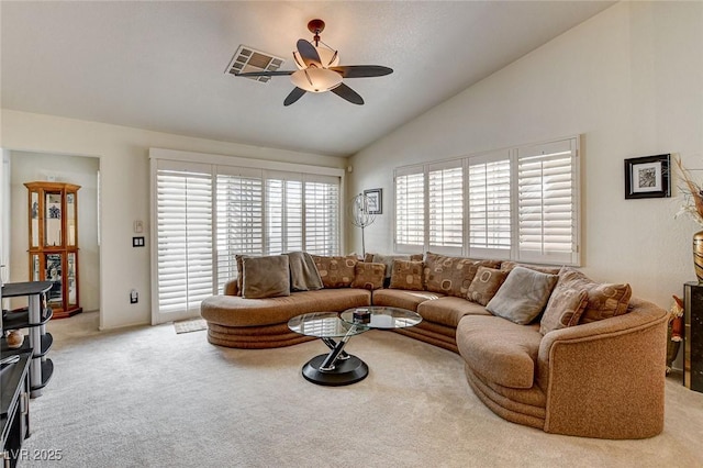 living area featuring lofted ceiling, ceiling fan, visible vents, and light colored carpet