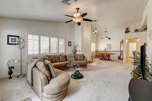 living room featuring light carpet, high vaulted ceiling, ceiling fan, and visible vents