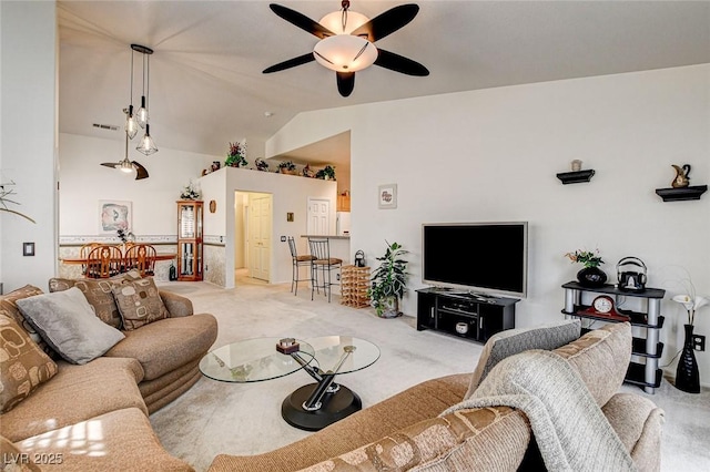 living room with visible vents, vaulted ceiling, a ceiling fan, and light colored carpet