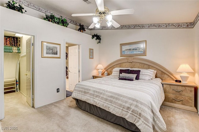 bedroom with ceiling fan, light carpet, visible vents, a spacious closet, and ensuite bath