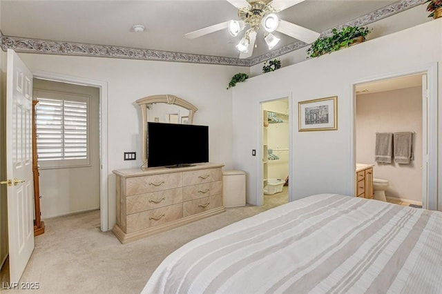 bedroom with light carpet, connected bathroom, and ceiling fan