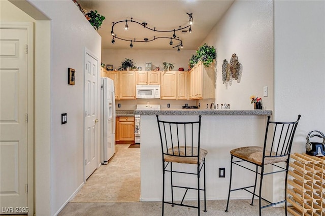 kitchen featuring light countertops, light brown cabinets, white appliances, a peninsula, and a kitchen breakfast bar