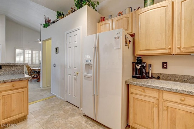 kitchen featuring white refrigerator with ice dispenser, light tile patterned floors, a ceiling fan, light brown cabinets, and light stone countertops