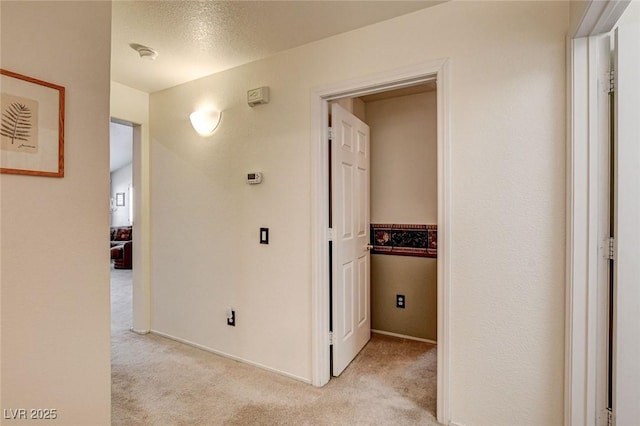 corridor with light carpet and a textured ceiling