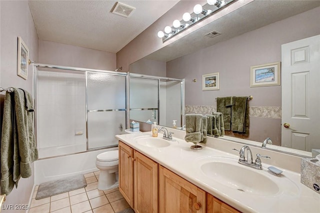 full bathroom featuring a textured ceiling, a sink, visible vents, and tile patterned floors